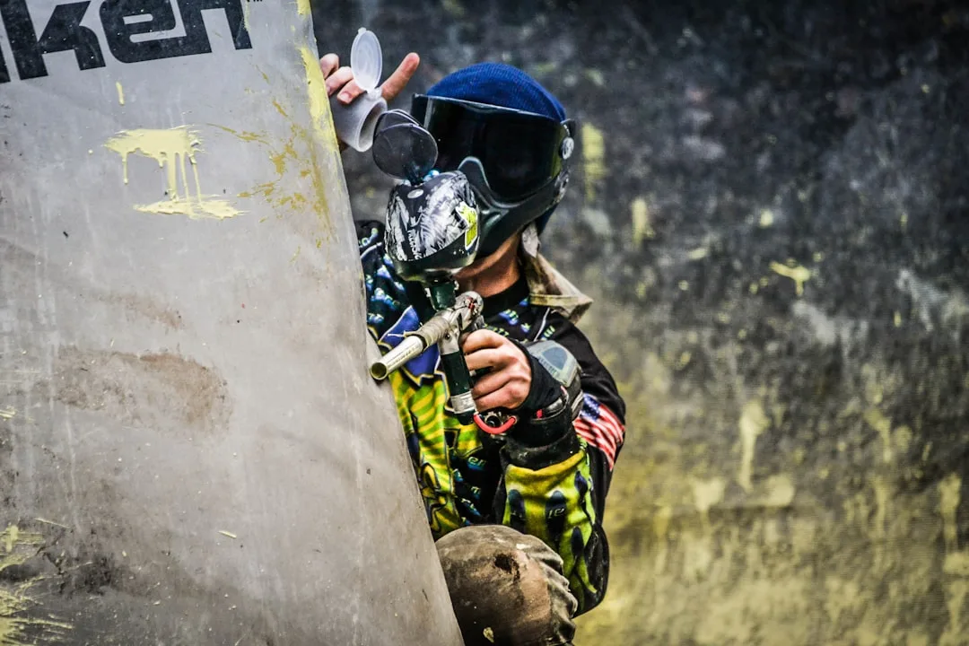 Employé souriant en équipement de paintball levant le pouce après sa victoire