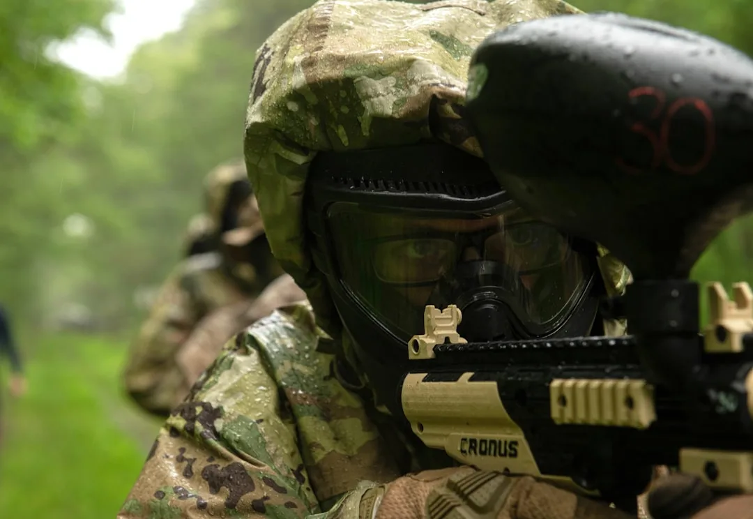 Équipe d'entreprise en tenue tactique jouant au paintball en extérieur lors d'une sortie de groupe