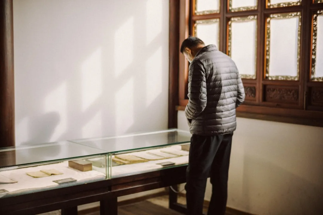 Un scénographe examine une maquette de vitrine en bois avec son client dans un bureau.